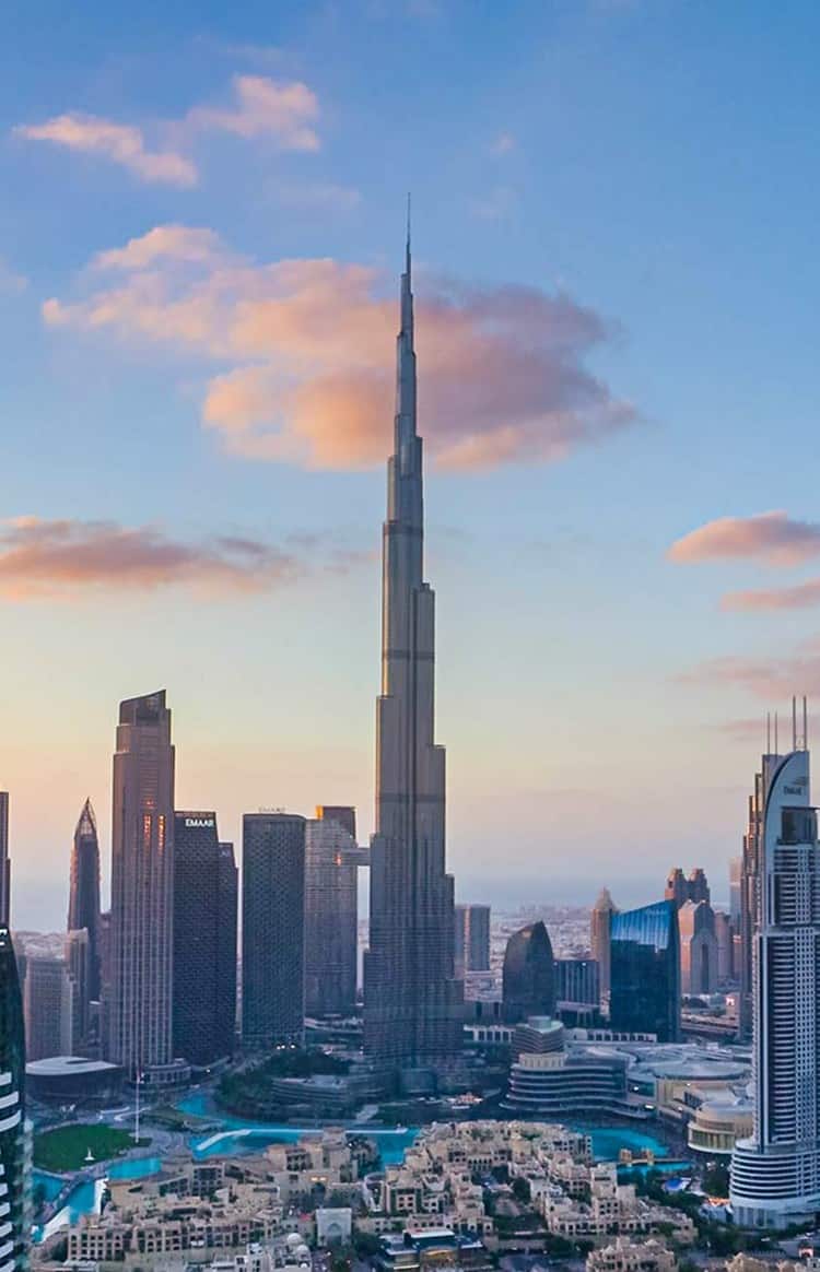 Panoramic view of the Downtown Dubai skyline and Burj Khalifa under a warm sunset sky