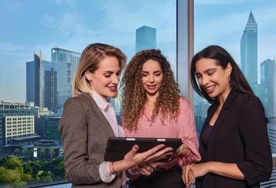 Three professionals looking at a tablet against a city backdrop